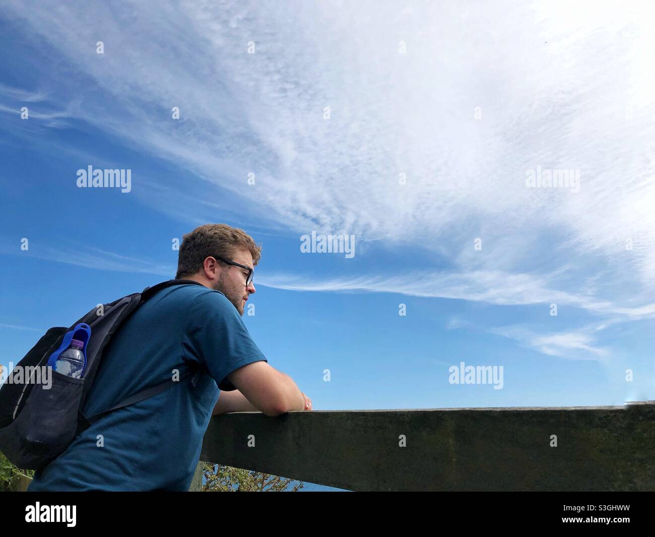 Blick aus der unteren Perspektive eines männlichen Wanderers, der einen Rucksack trägt und bei einem langen Spaziergang die Aussicht bewundern kann Stockfoto