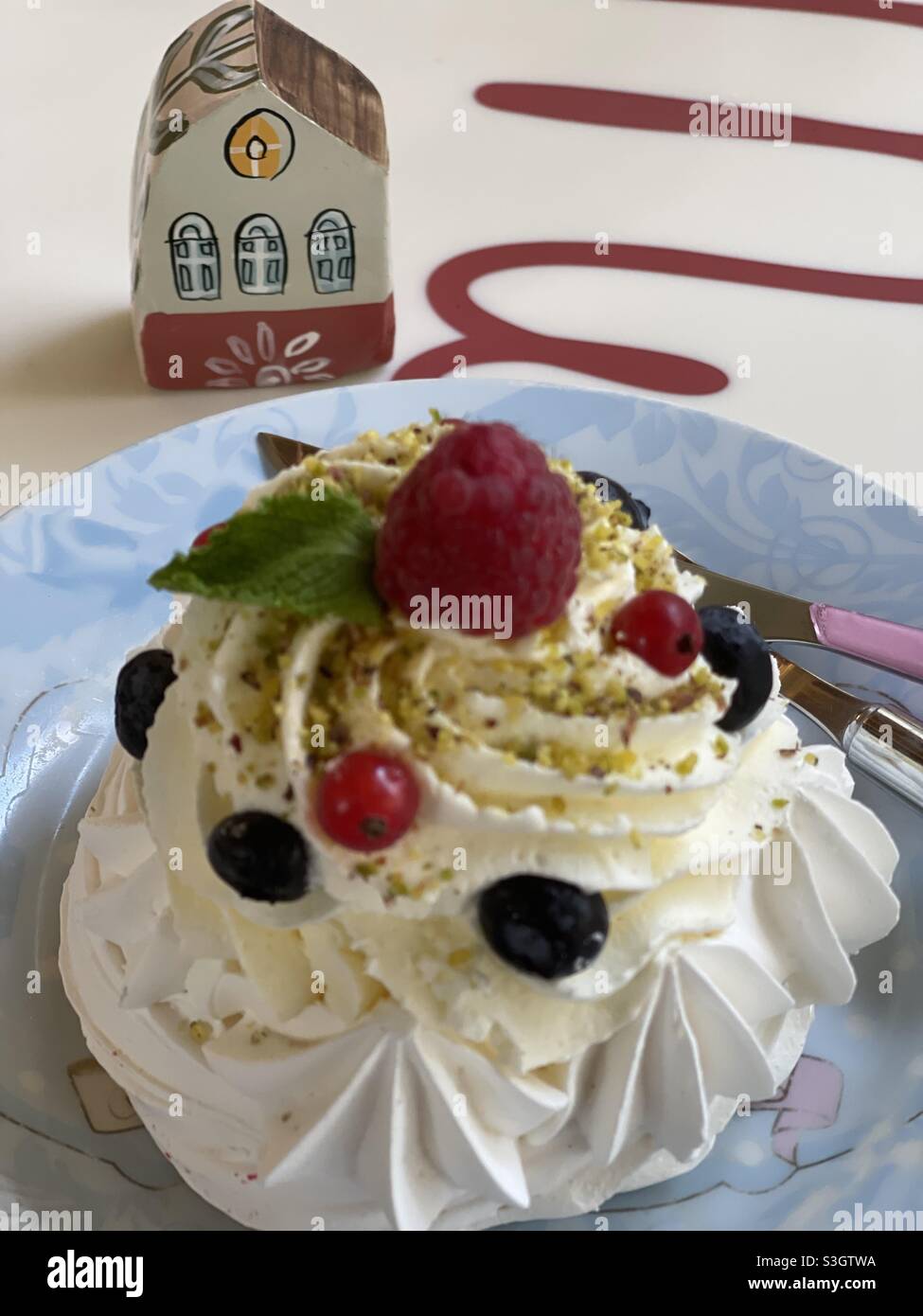 Baiser-Dessert mit Heidelbeeren, Creme und einem handgefertigten Miniaturhaus Stockfoto