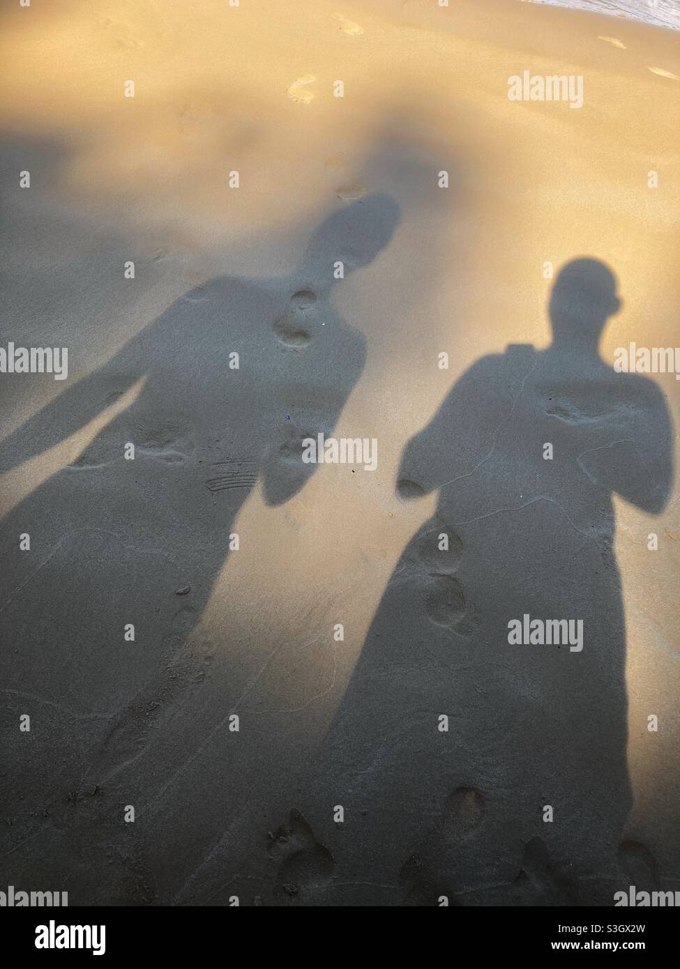 Die Schatten zweier Männer mittleren Alters an einem gelben Strand Stockfoto