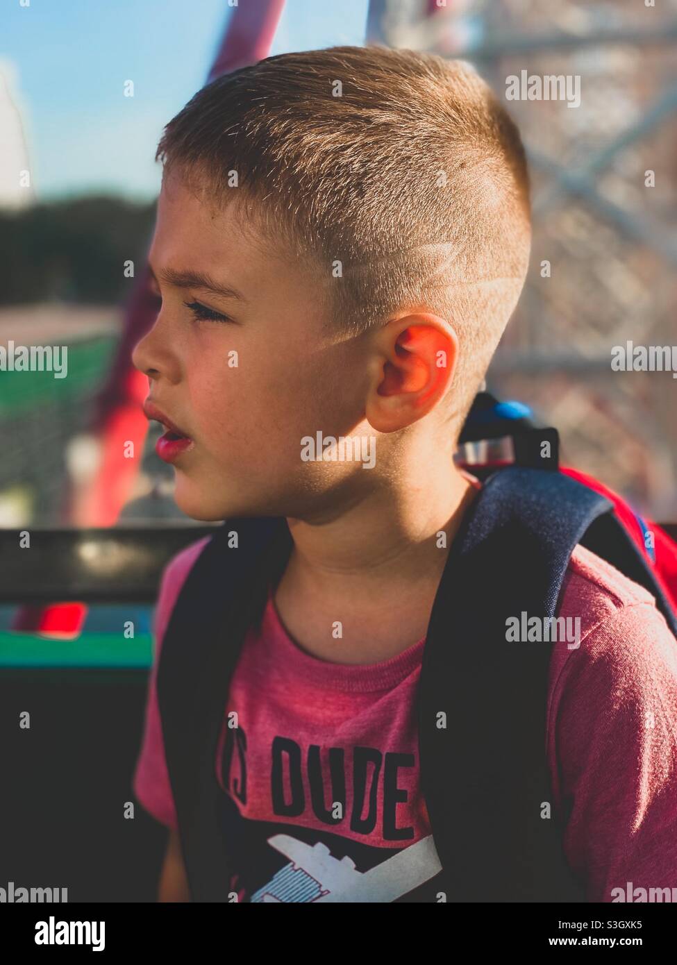 Die fünfjährige sitzt auf einem Riesenrad und schaut sich die verschiedenen Attraktionen an Stockfoto