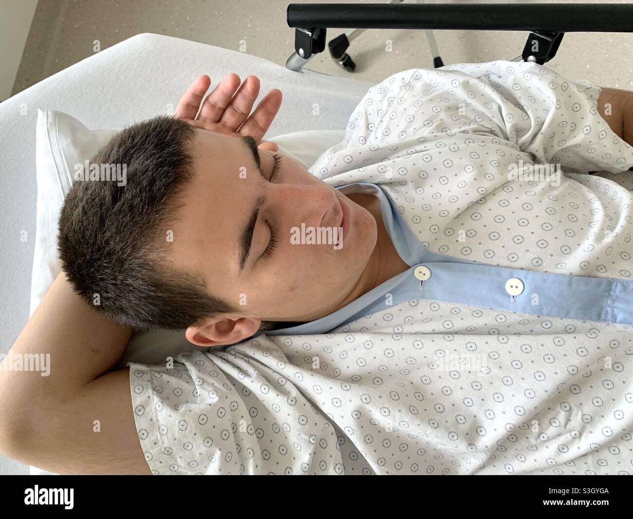 Patient schläft im Krankenhaus vor der Operation. Er wird operiert werden. Er trägt ein Krankenhauskleid. Stockfoto