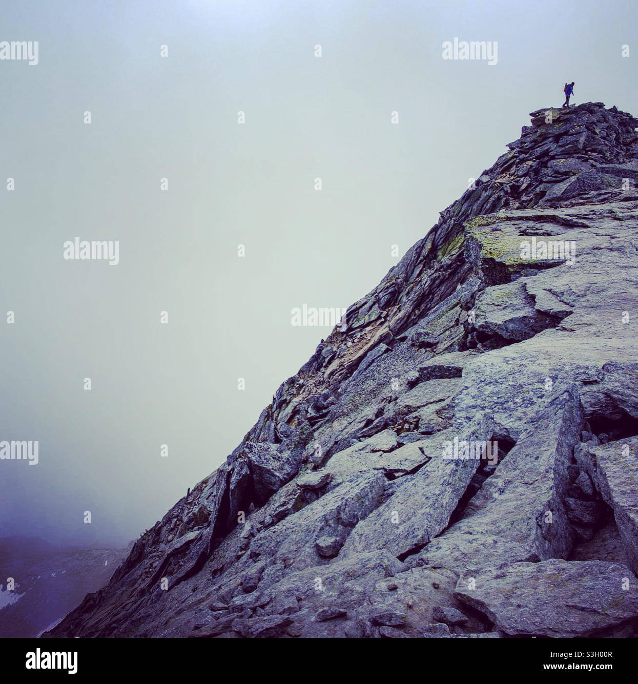 Bergsteiger auf einem felsigen Berg an einem nebligen Tag - Smartphone-aufgenommenes Stockfoto