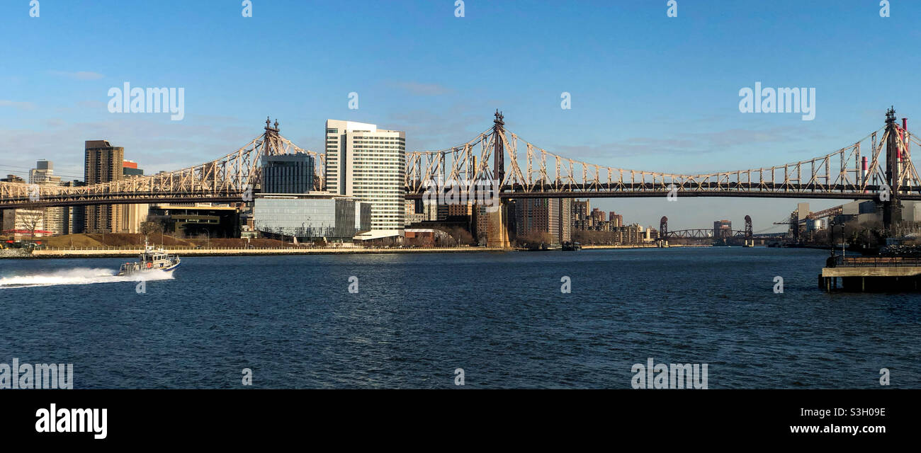 Ein Boot führt an Roosevelt Island vorbei zur Queensboro-Brücke und zum Tata Innovation Center Stockfoto