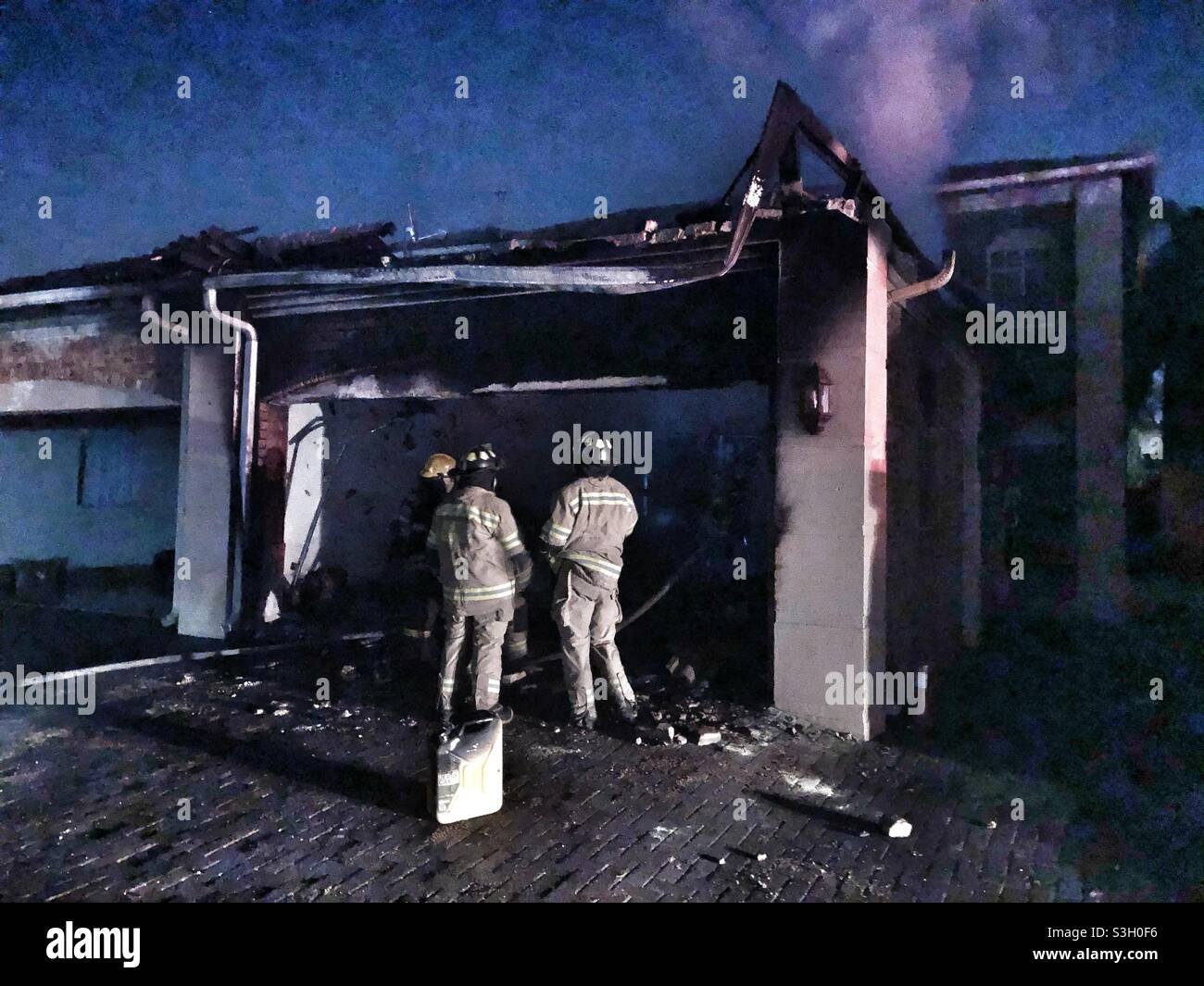Feuerwehrleute, die das verbrannte Gebäude nach einem Hausbrand vermessen Stockfoto