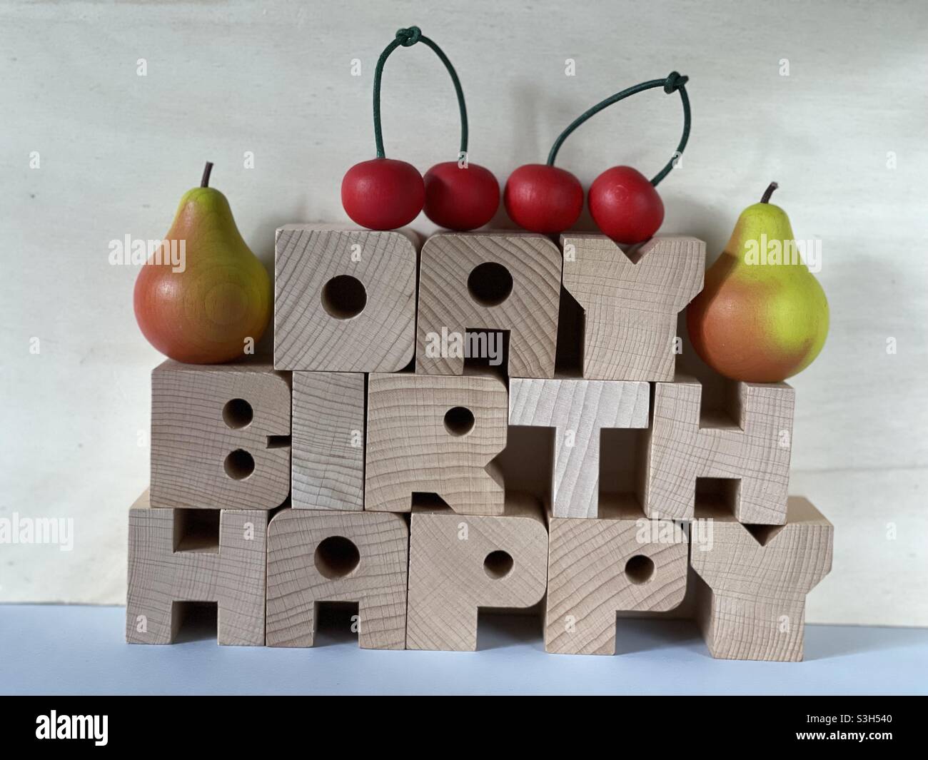 Happy Birthday Text mit handgefertigten Holzbuchstaben mit kunstvollen Holzkirschen und Holzbirnen Stockfoto