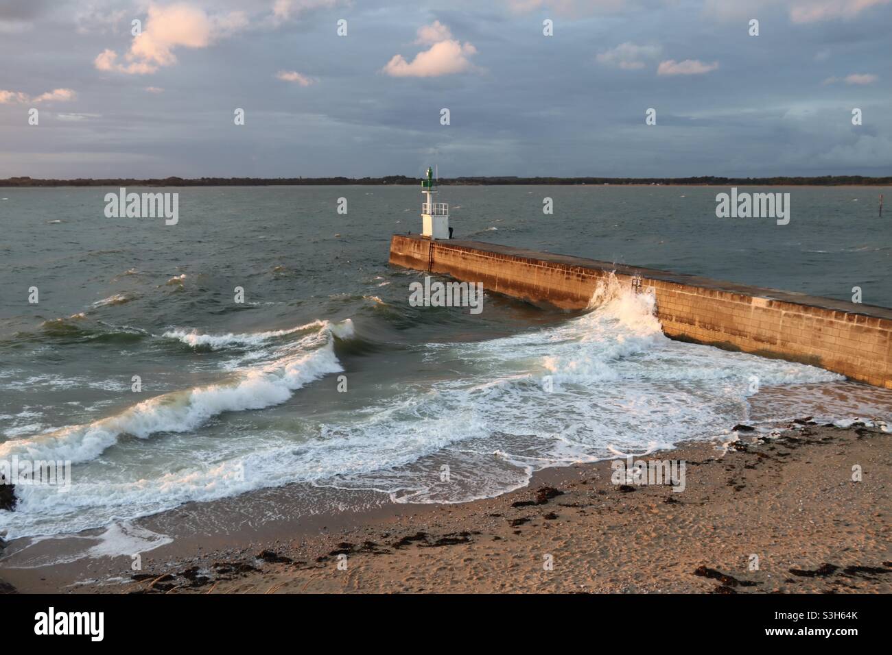 Am Sommer 2021 planschen Wellen am Pier bei Sonnenuntergang in Merquel, Departement Loire Atlantique in Frankreich - Smartphone-aufgenommenes Stockfoto