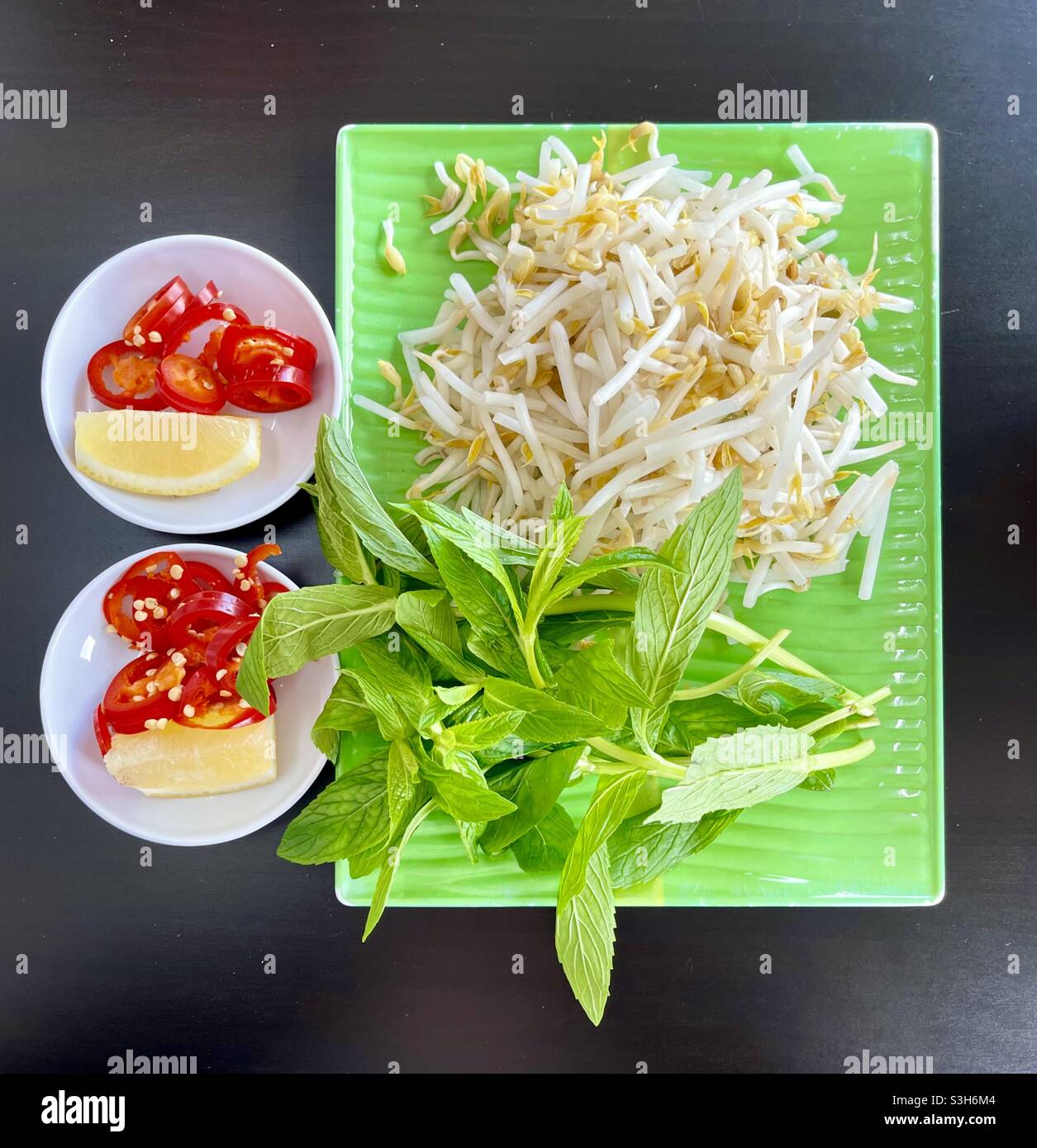 Würze rote Chilischoten, Zitronenkeile, Minzblätter und Bohnensprossen, die in vietnamesischer Pho-Nudelsuppe verwendet werden Stockfoto
