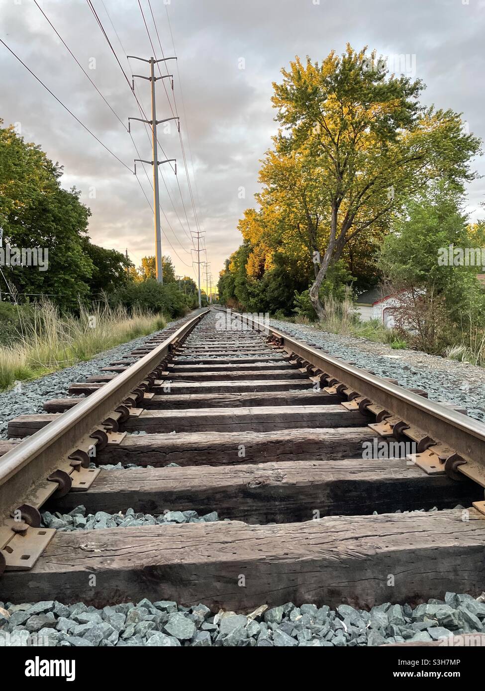 Eisenbahnschienen in Minnesota. Eisenbahnverbindungen und Stromleitungen zum Fluchtpunkt an einem Sommerabend im mittleren Westen. Stockfoto