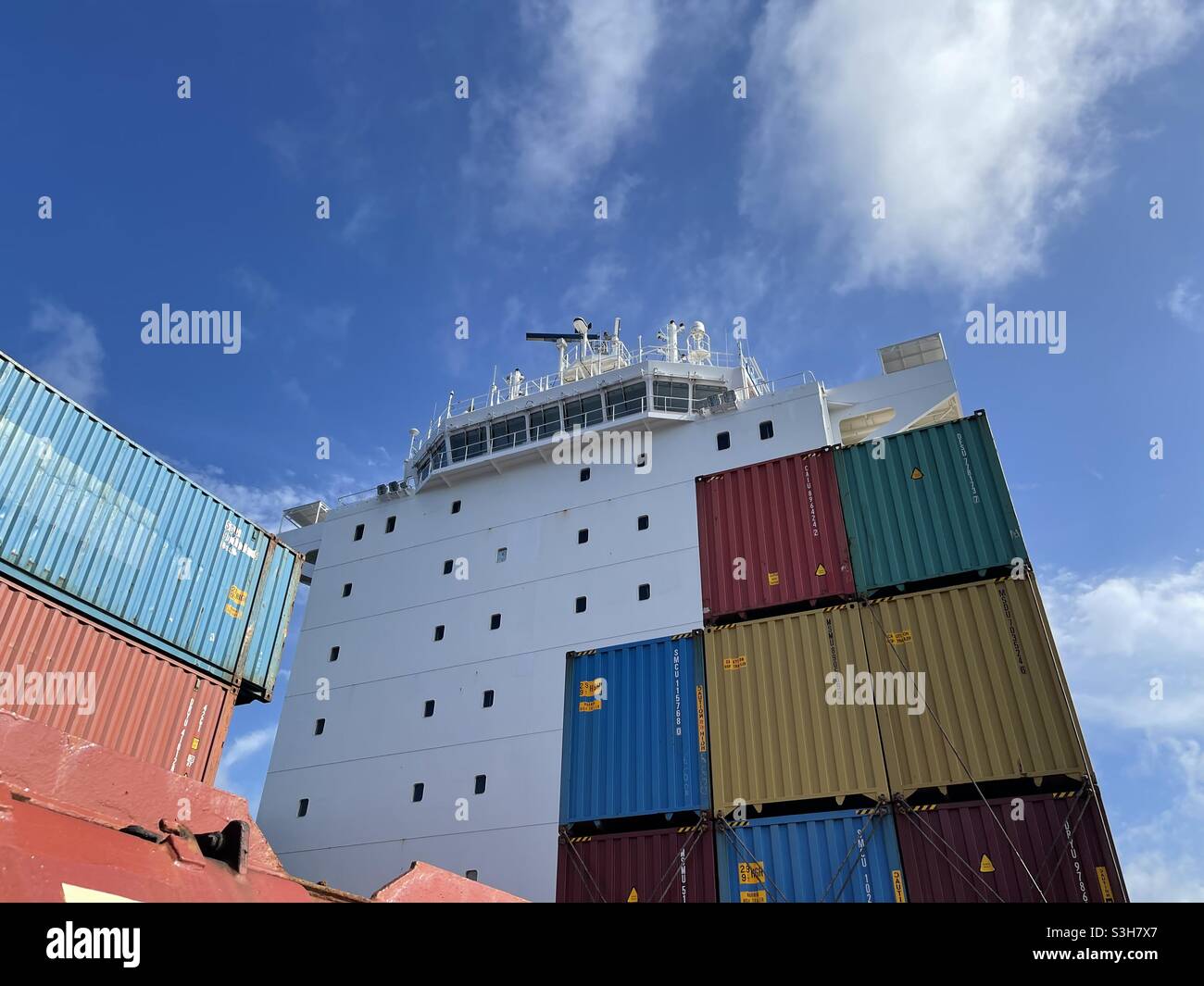Weißer Überbau mit Navigationsbrücke des laufenden Containerschiffes, beladen mit Containern verschiedener Spediteure. Stockfoto