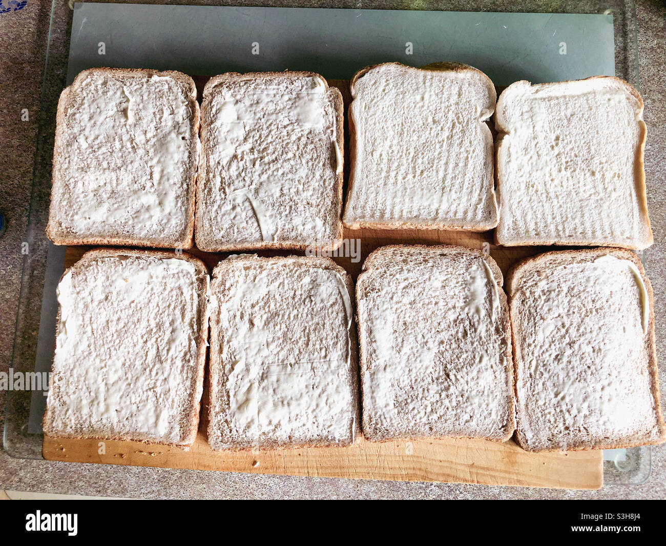 Scheiben gebuttertes Brot auf einem Brottafel auf einer Küchenarbeitsplatine. Stockfoto