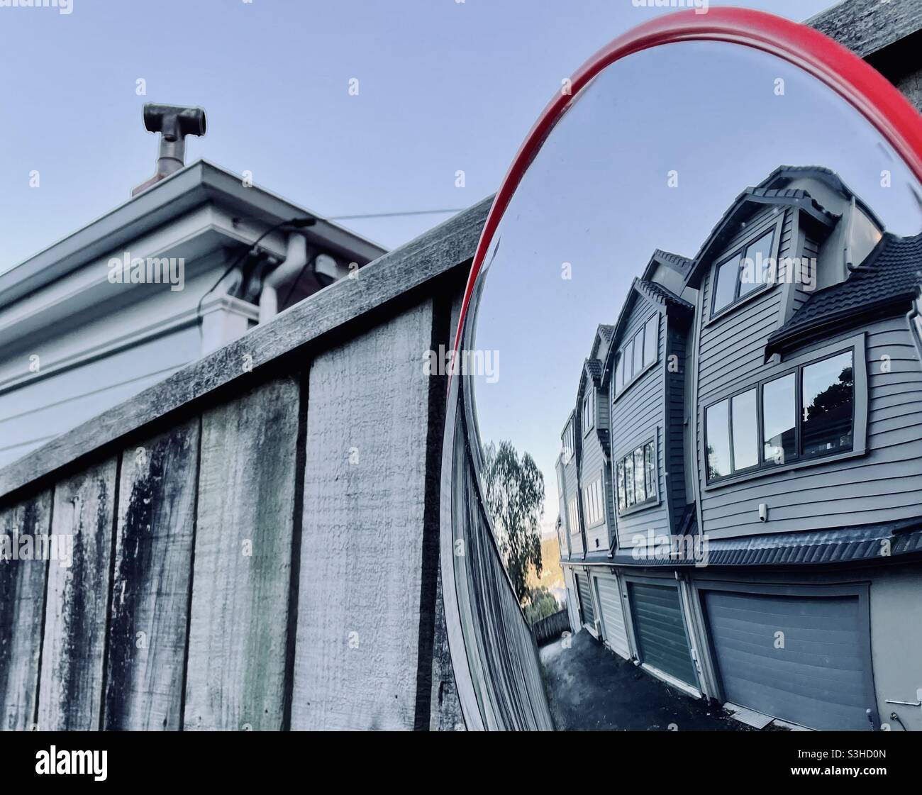 Das Dach eines alten lärmenden und neueren Gehäuses mittlerer Dichte spiegelt sich in einem Spiegel in Wellington, Neuseeland, wider Stockfoto