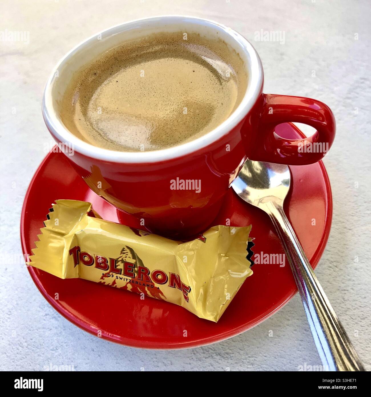 Tasse frischen Kaffee mit einem kostenlosen Miniatur-Toblerone-Verkoster. Stockfoto