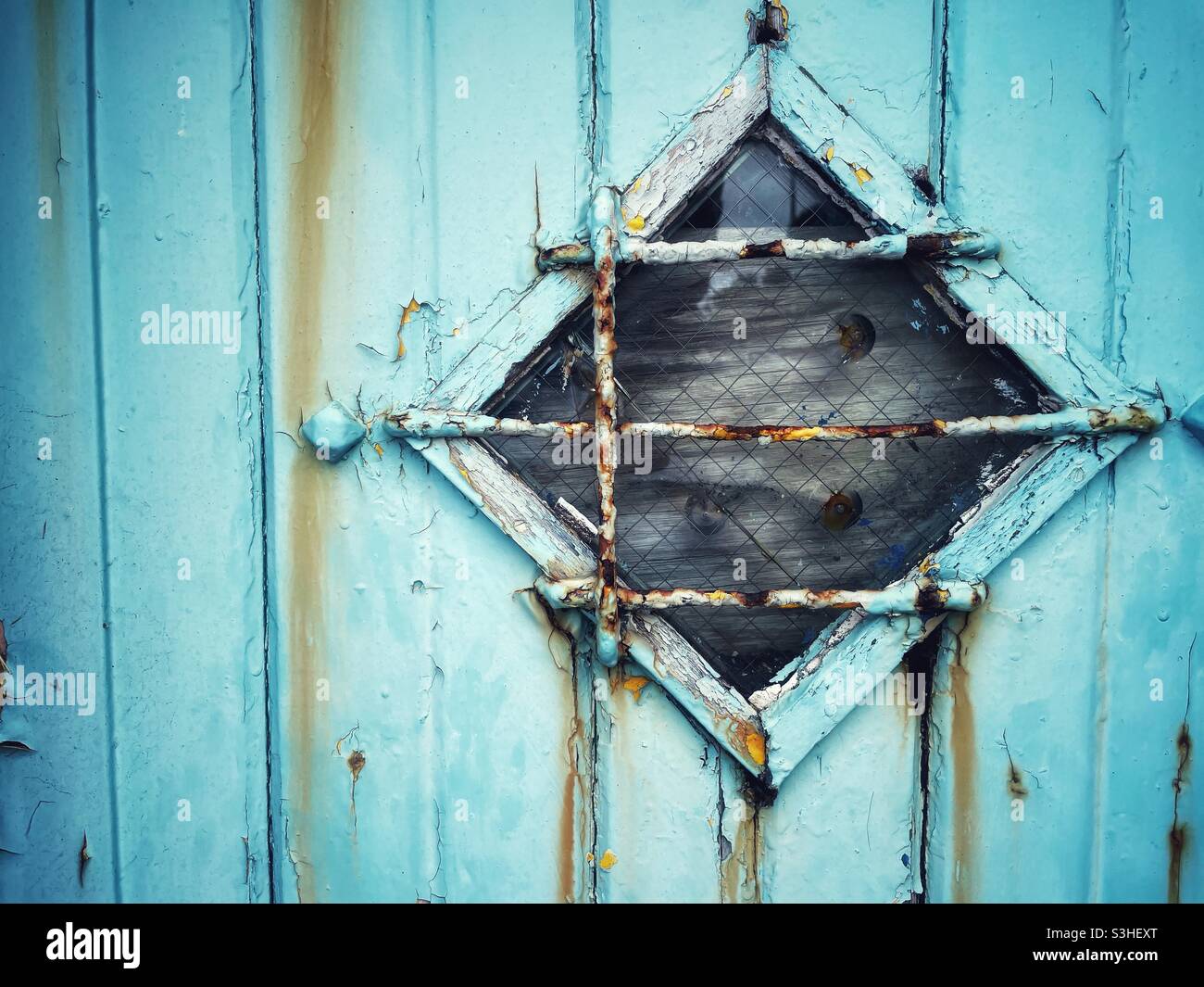 Alte verwitterte Tür mit Diamantenfenster. Stockfoto