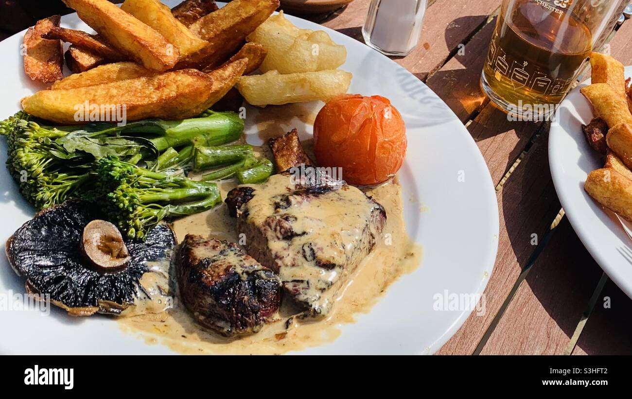 Steak, Chips, Pilze, Tomaten, Brokkoli und Pfeffersauce Stockfoto