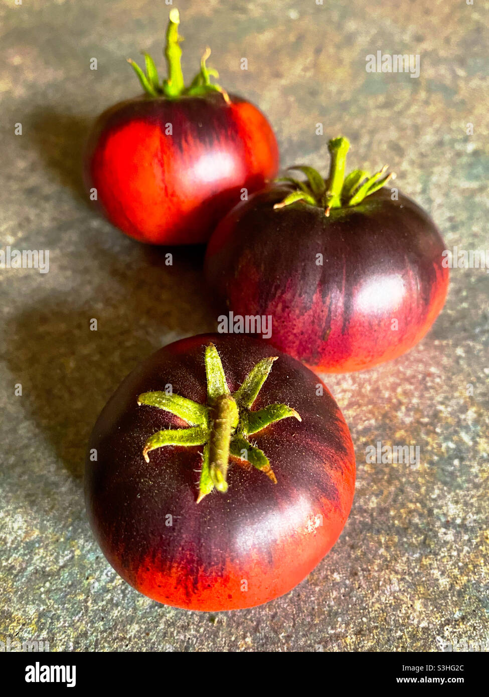 Drei Erbstücke Tomaten auf einer glatten Granitoberfläche Stockfoto