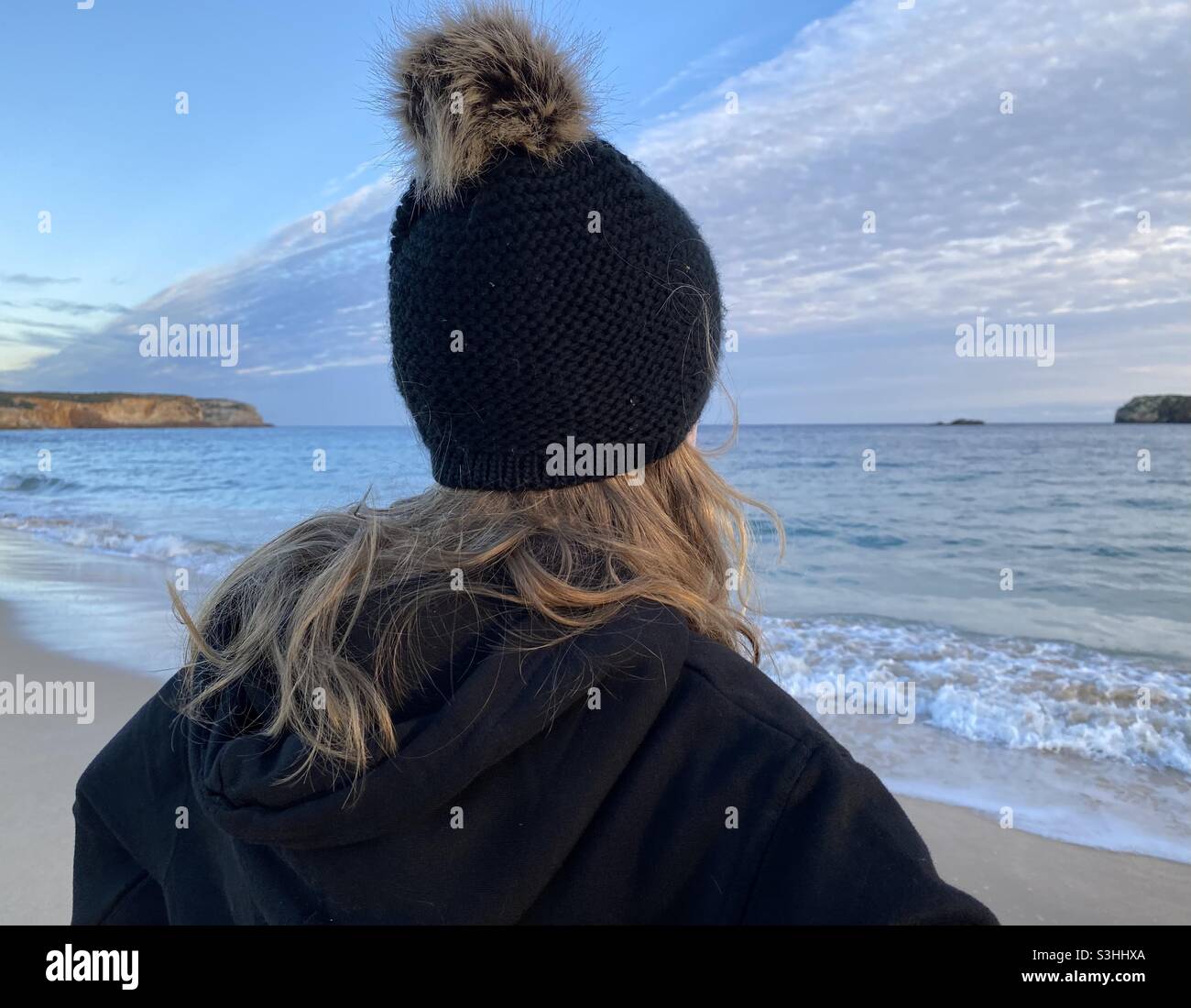 Mädchen trägt einen schwarzen Bommel Hut am Strand im Winter Stockfoto