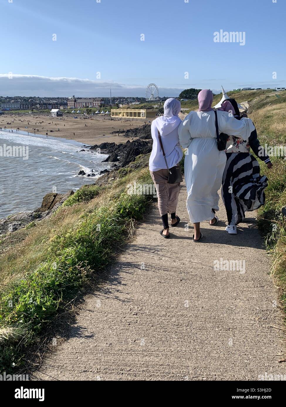 Muslimische Frauen, die an der Küste von Barry Island Cardiff Wales entlang wandern Stockfoto