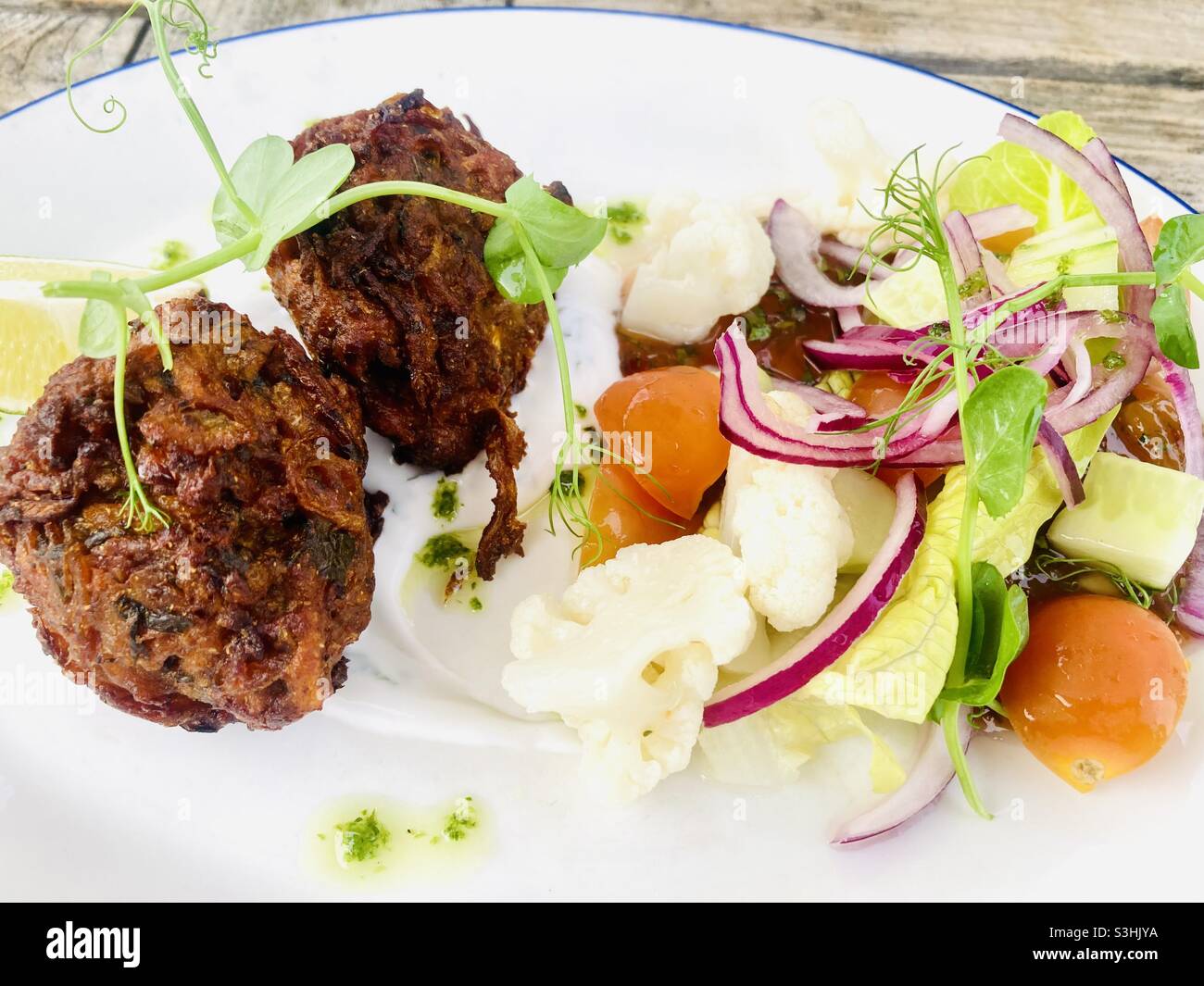 Indische Zwiebel Bhajis mit Salat Stockfoto