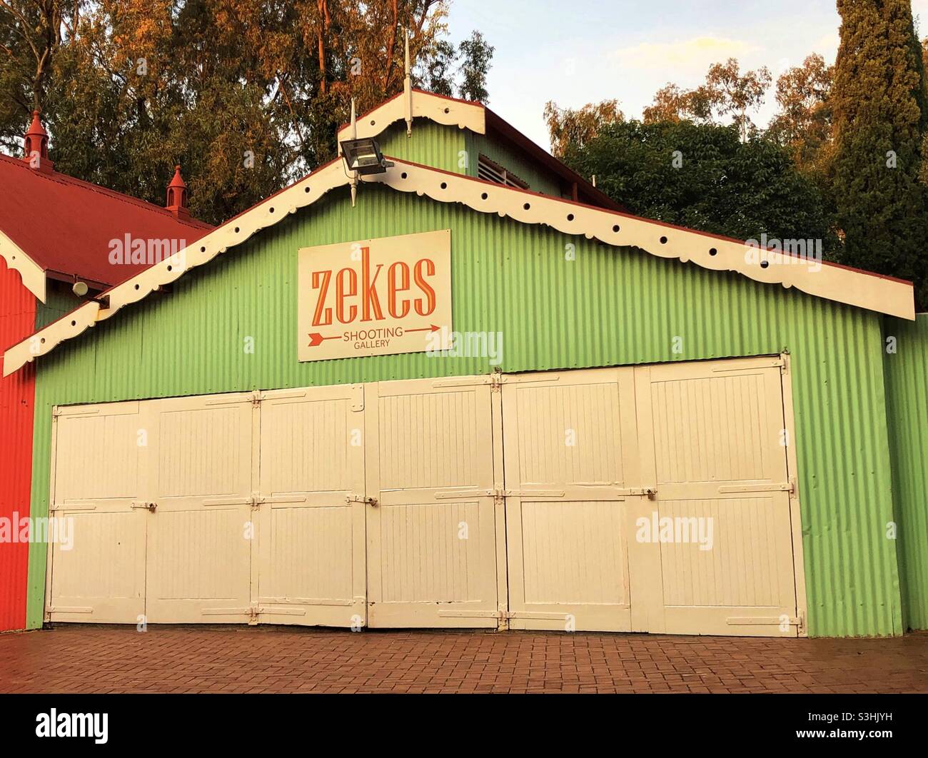 Grüner Schuppen mit weißen Türen und einem Schild mit der Aufschrift Zekes Shooting Gallery - Smartphone-aufgenommenes Stockfoto