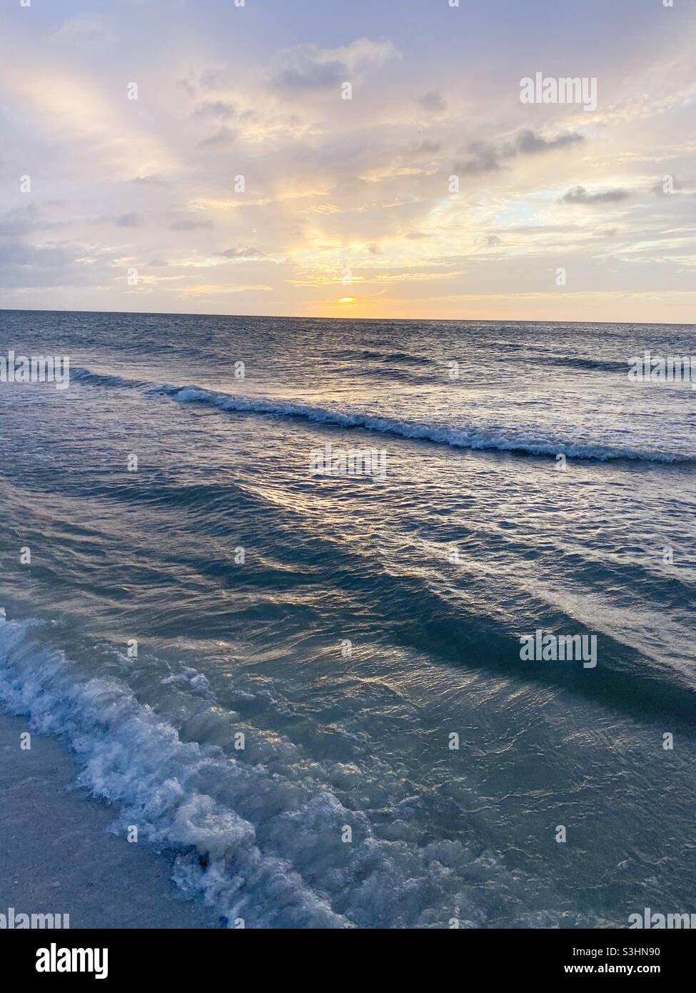 Wellen krachen während des Sonnenuntergangs ans Ufer Stockfoto