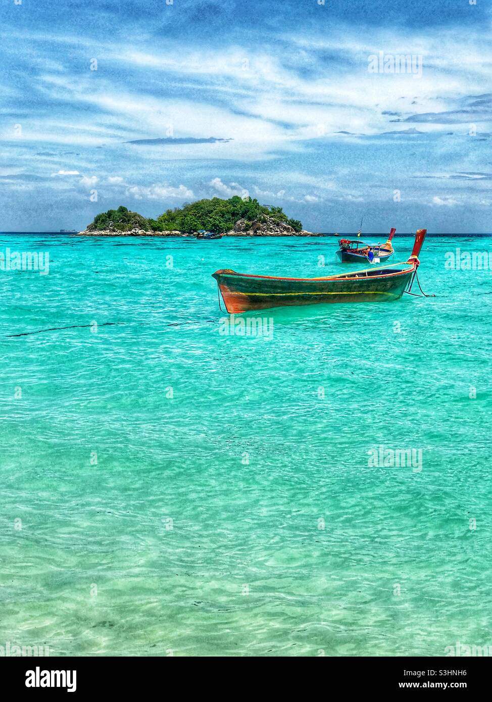 Vertikale Ansicht von Langschwanz-Booten, die in klarem Wasser auf Koh Lipe, Südthailand, verankert sind Stockfoto