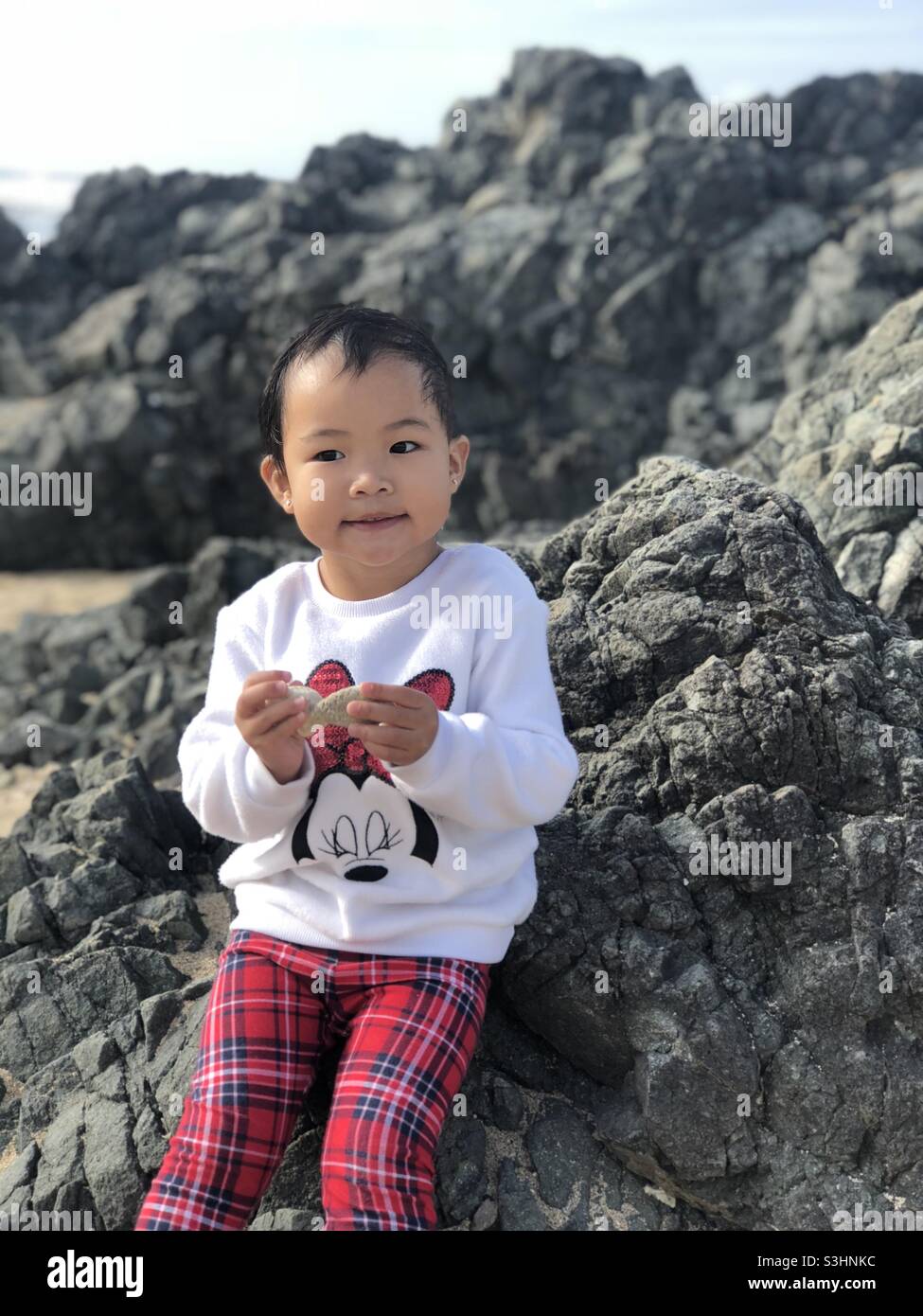 Das kleine Mädchen hat einen Moment auf dem Felsen. Stockfoto