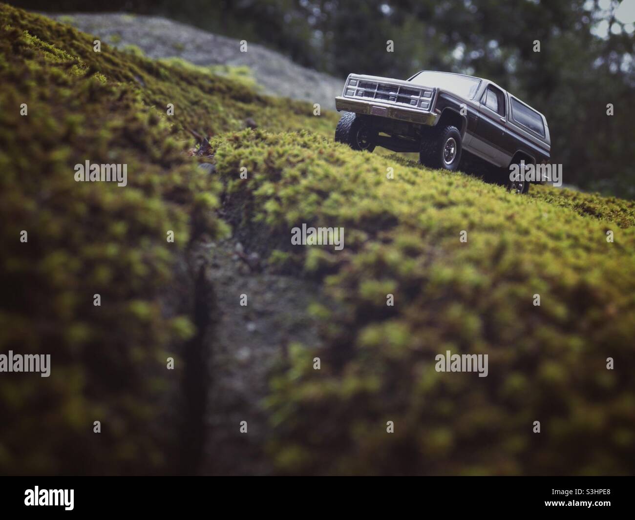 Ein Spielzeug-SUV klettert einen moosigen Hügel hinauf. Stockfoto