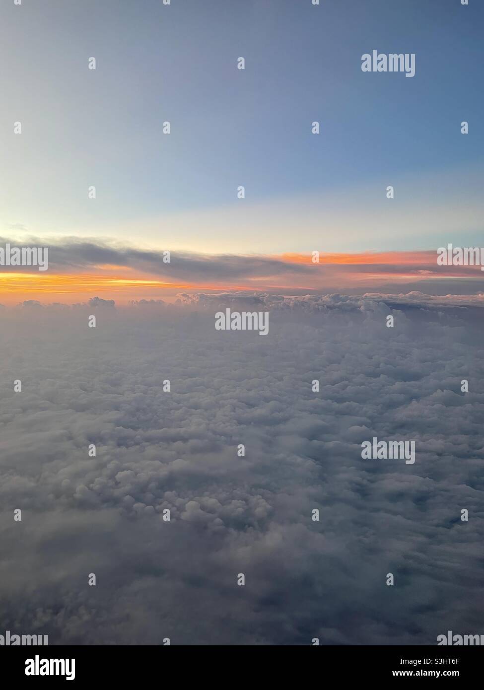 Ein Blick auf Wolken aus einem Flugzeug während eines frühen Morgensonnenaufgangs Stockfoto