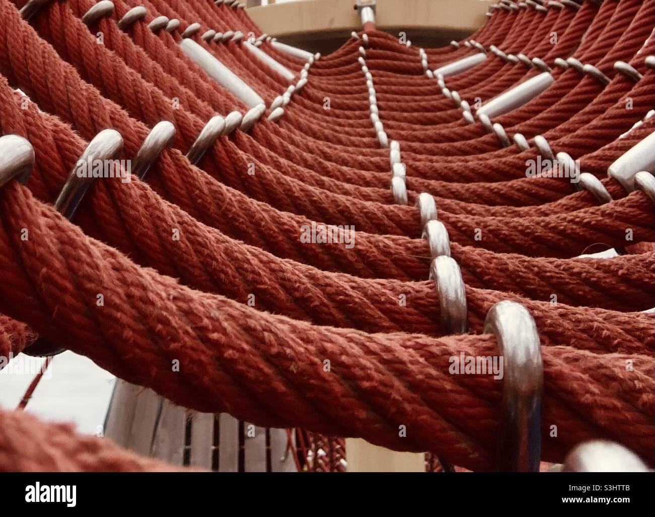 Rotes Seil mit Metallklammern an einem Netz befestigt - Smartphone-aufgenommenes Stockfoto