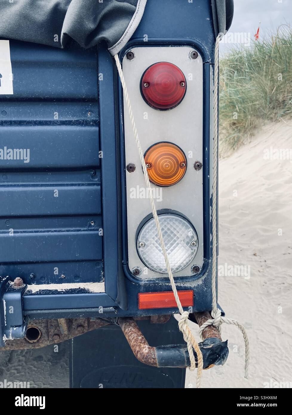 Die vertikale Rücklicht-Bar eines alten blauen Land Rover am Strand Stockfoto