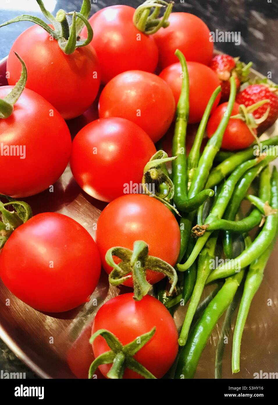 Hausgemachte, leuchtend rote Tomaten und saftig grüne, würzige Chilischoten Stockfoto
