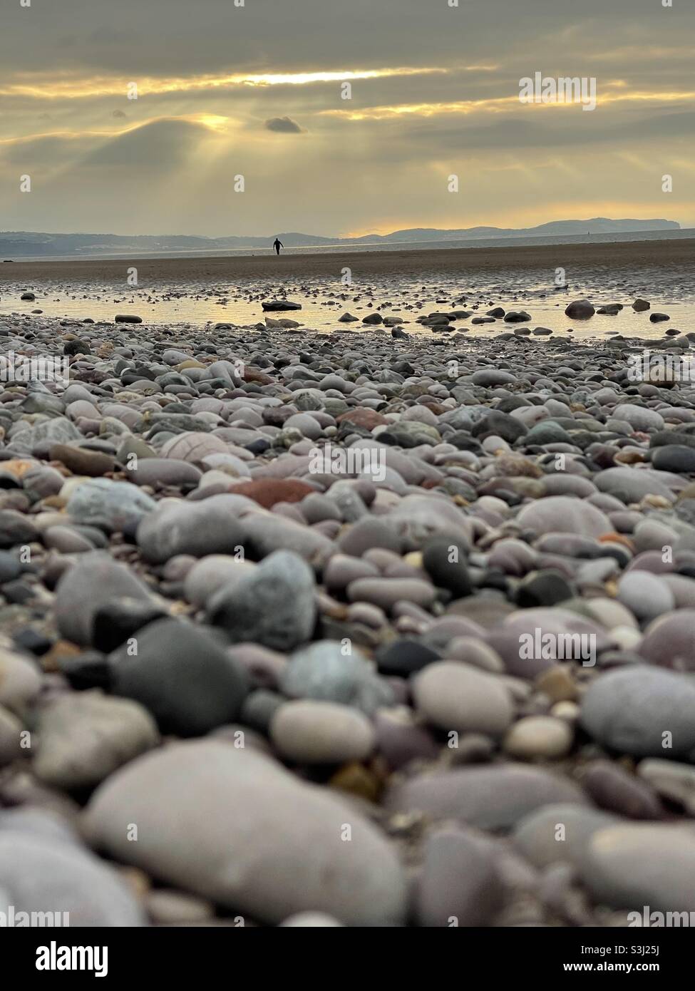 Sonnenuntergang an einem steinigen Strand Stockfoto