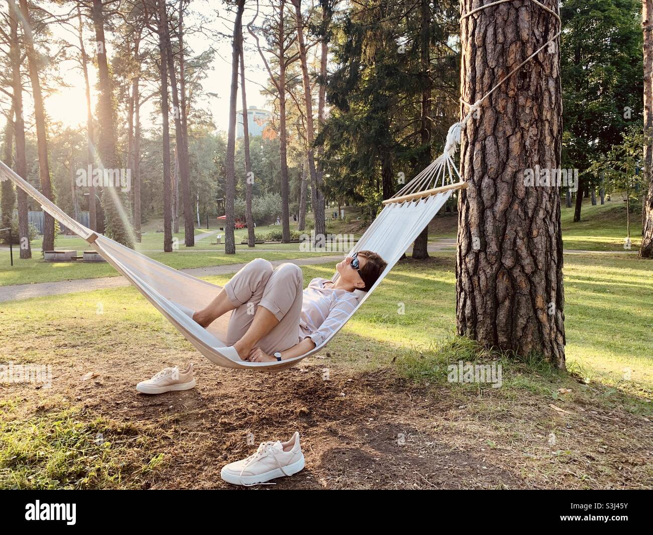 Frau mittleren Alters, die sich im Sommer in der Hängematte im Park entspannt Stockfoto