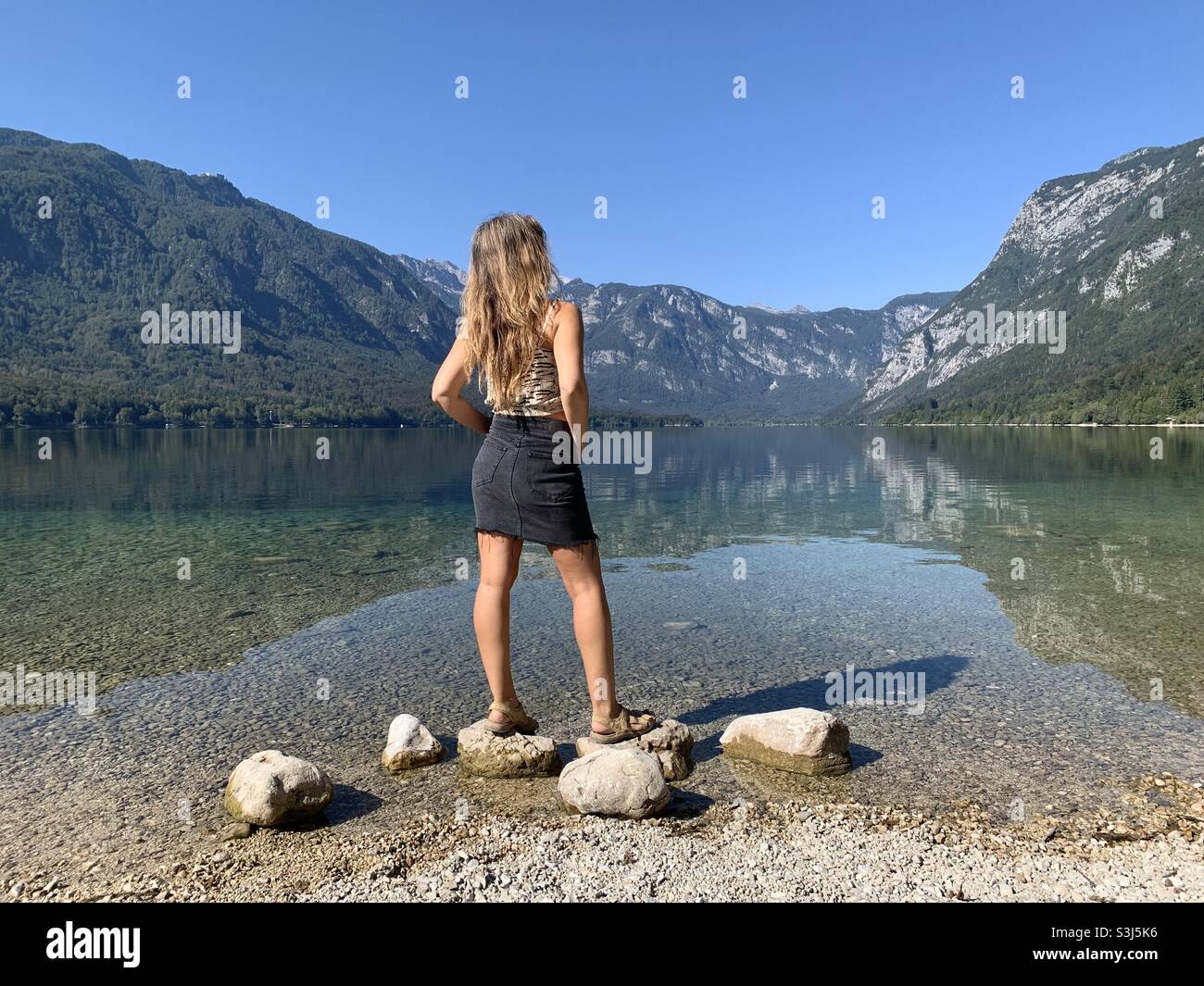 Frau, die auf einem Felsen am Ufer des bohinjer Sees steht Stockfoto