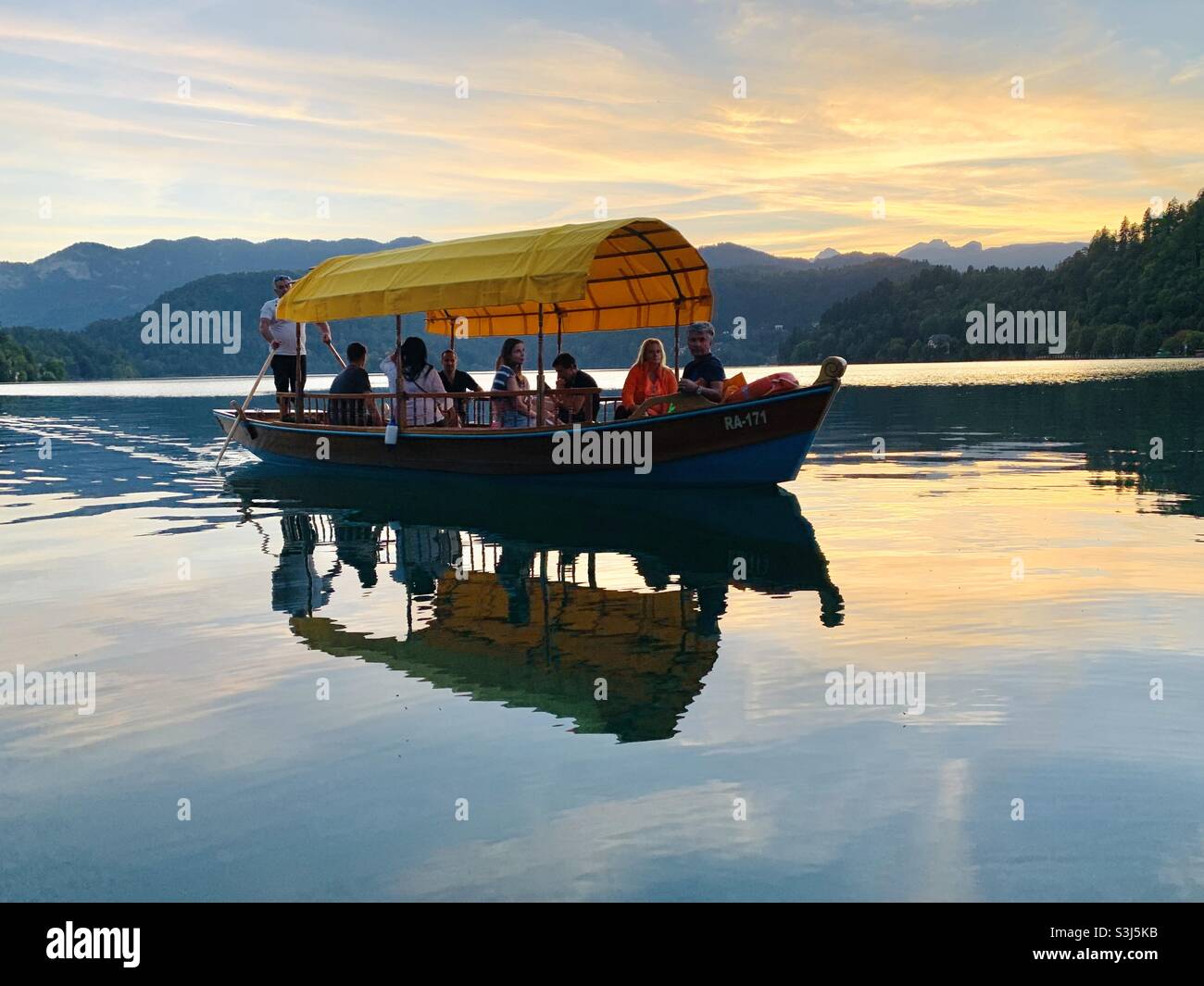 Boot bei Sonnenuntergang auf dem See blutete Stockfoto