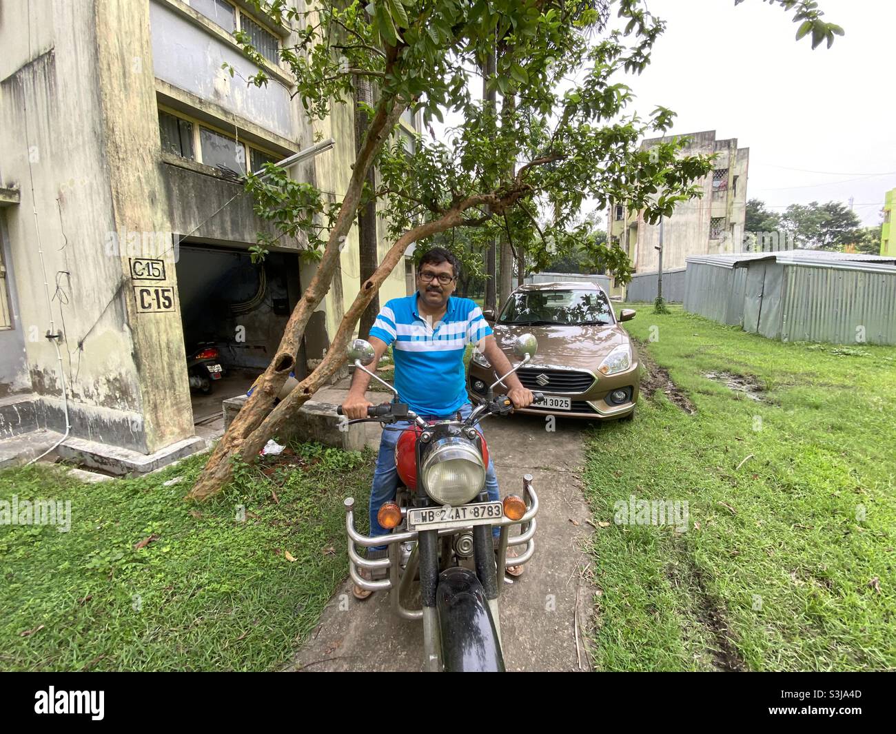 Ein indischer Mann sitzt auf einem Zweirad in einem Wohnkomplex Stockfoto
