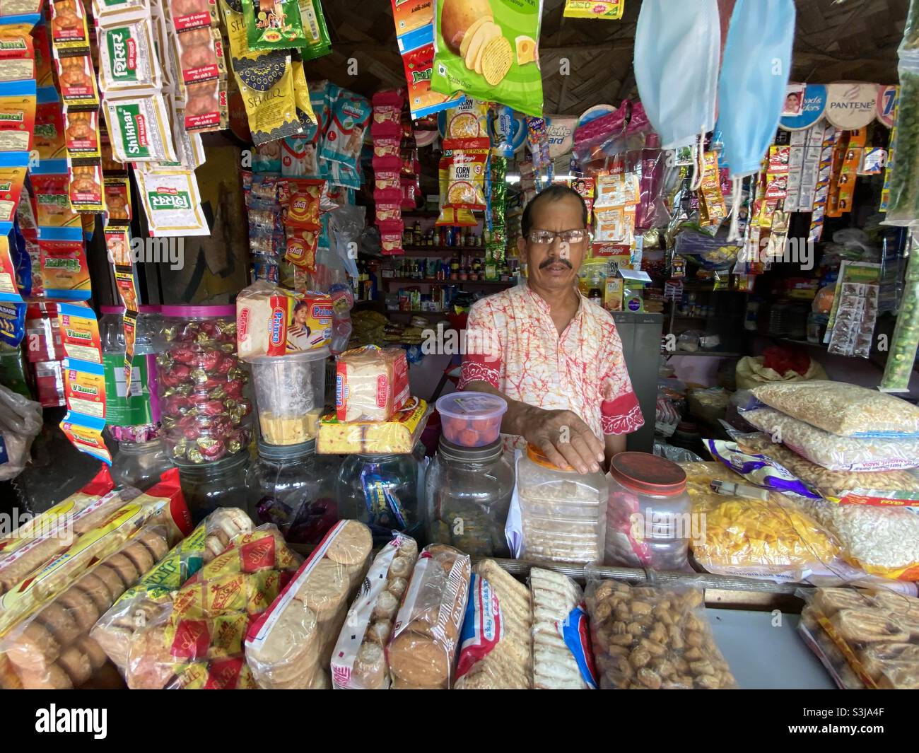 Ein indischer Kleinunternehmer, der in seinem Geschäft verschiedene Produkte verkauft Stockfoto