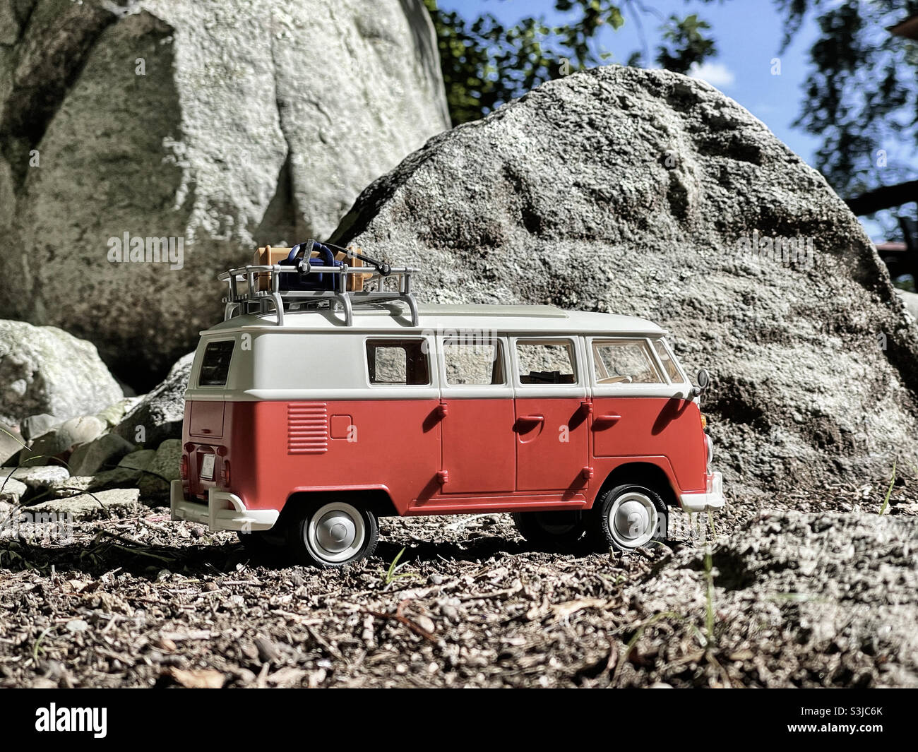 Ein Volkswagen-Spielzeugbus posierte neben einer interessanten Felsformation und fotografierte ihn aus einem niedrigen Winkel, um ihn wie die echte Sache aussehen zu lassen. Stockfoto