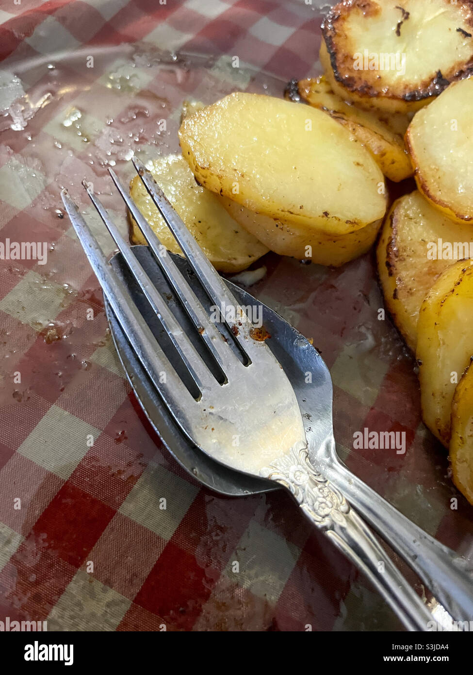 Besteck und Kartoffeln in einem durchsehenen Teller Stockfoto