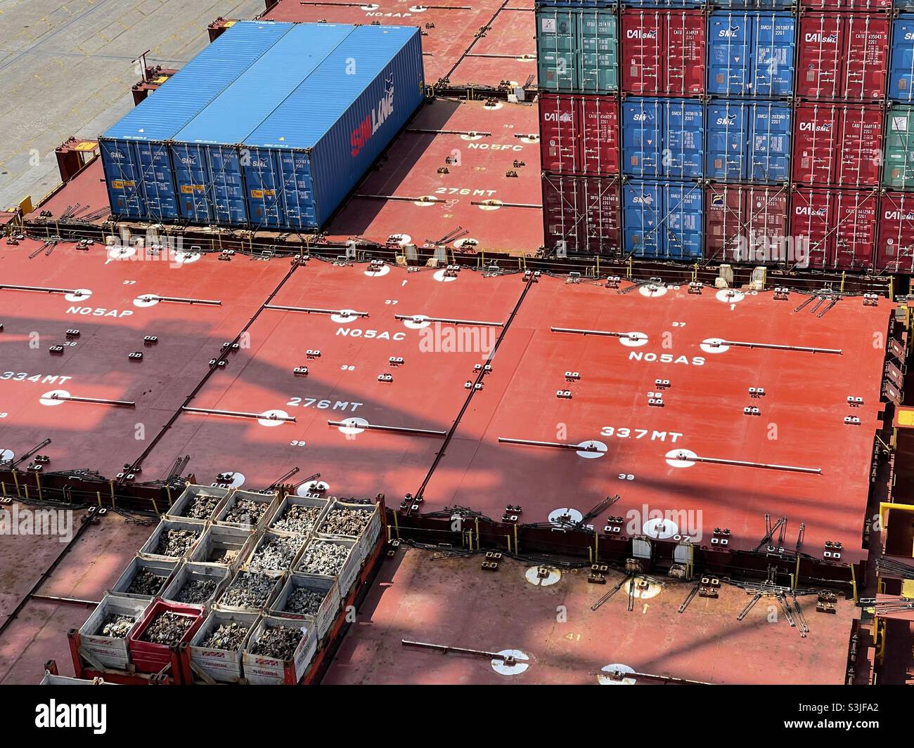 Lukenabdeckungen des Containerschiffes, beladen mit Containern und flacher Schiene mit Zurrmaterial, vertäut im Hafenterminal und wartet auf den Frachtbetrieb. Stockfoto