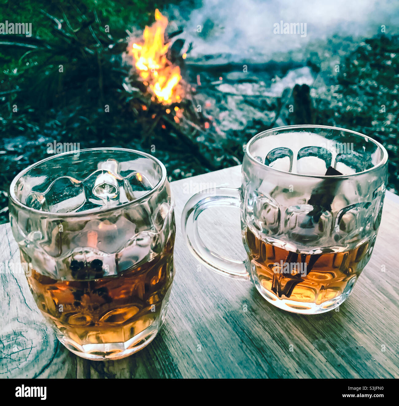 Heiße Toddies in Retro-Half-Pint-Gläsern am Lagerfeuer Stockfoto