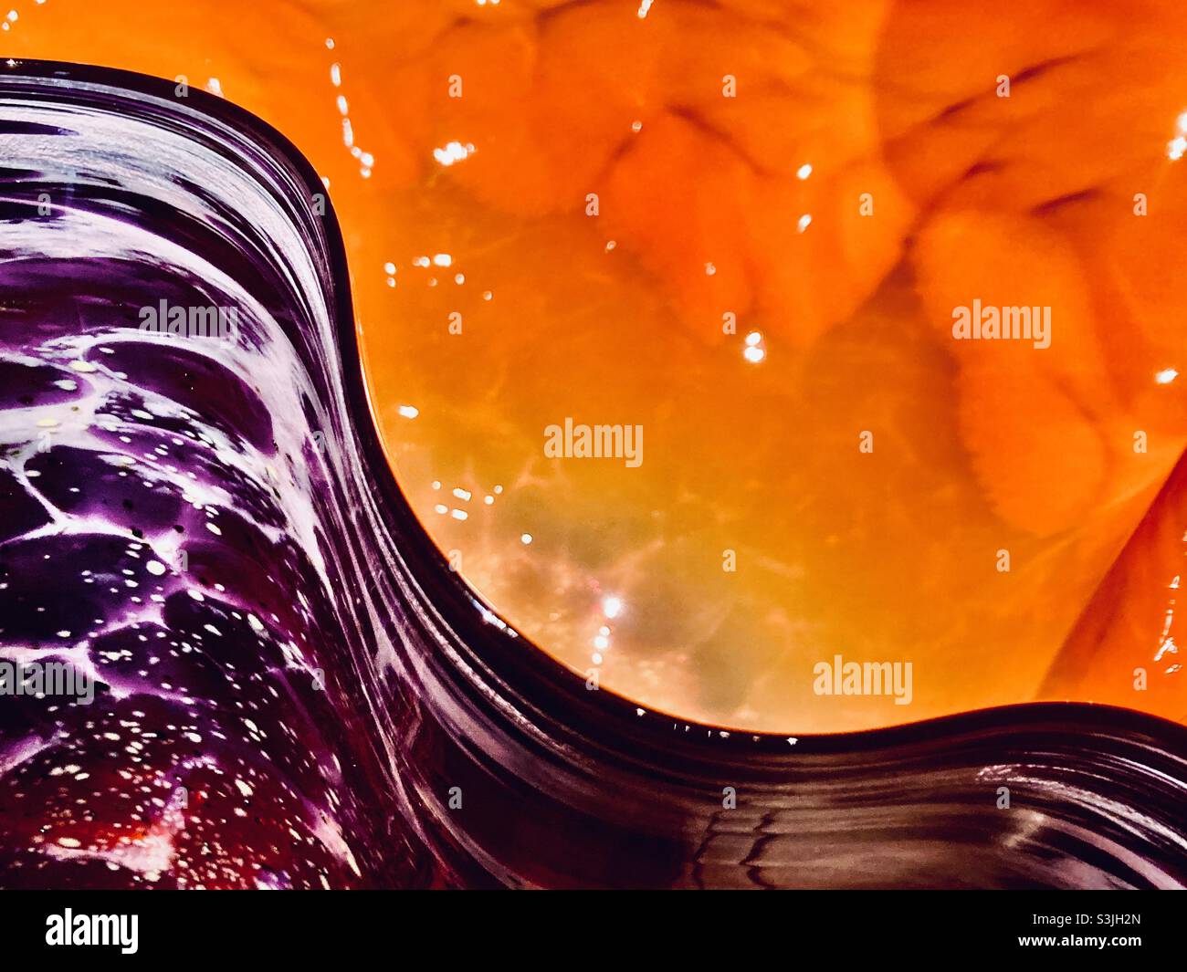 Buntes mundgeblasenes Glas im Wellendesign von Orange und Lila Stockfoto