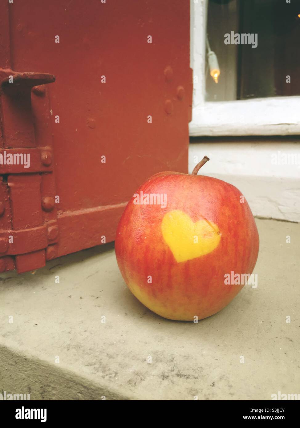 Roter Apfel mit Herz auf einer alten Sandsteinfensterschwelle Stockfoto