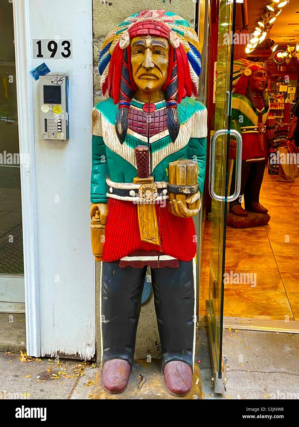 Ein Vintage-Holzschnitzwerk vor einer indianischen Statue in Soho, New York City, USA Stockfoto