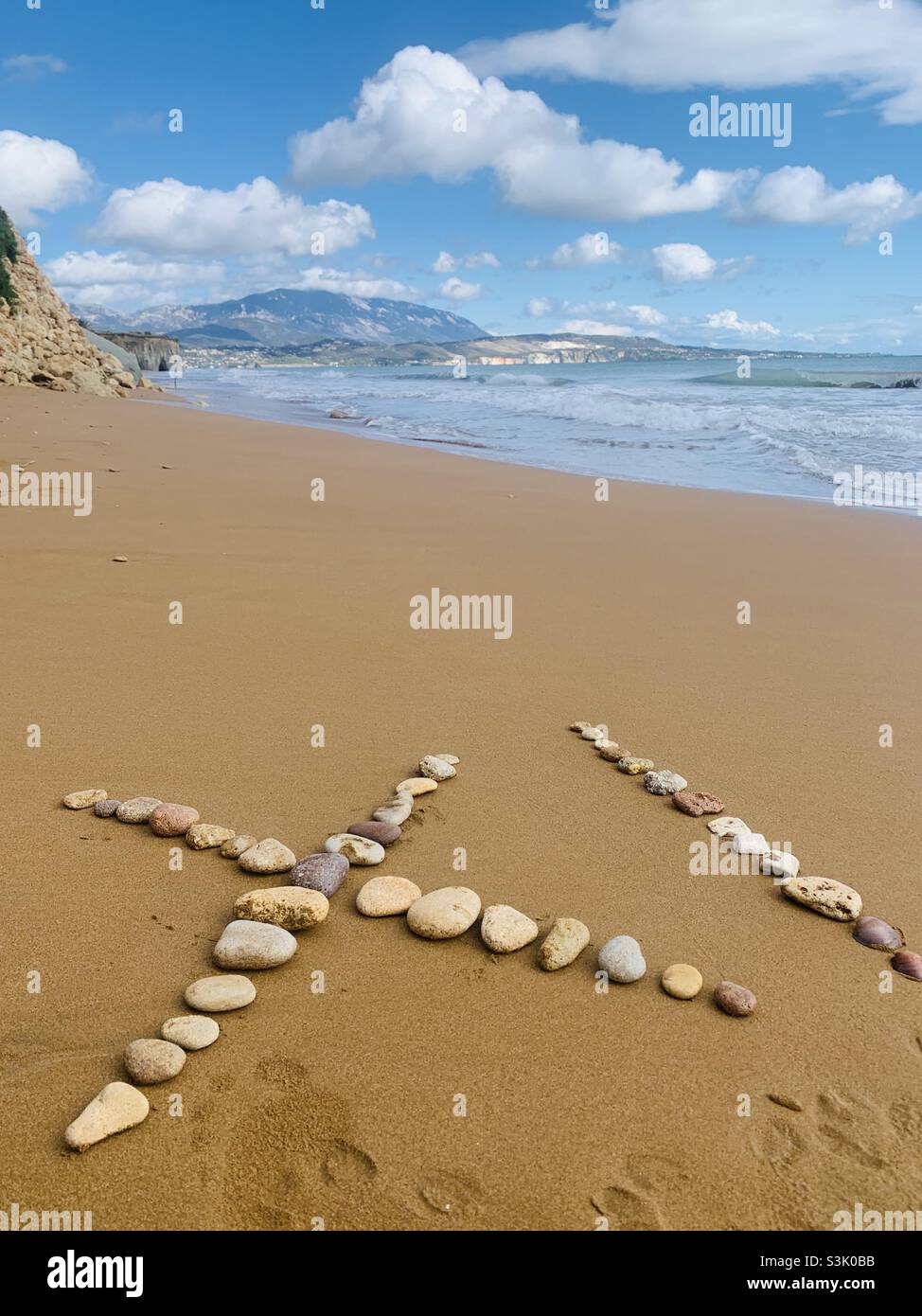 Steine, die Xi am Strand in kefalonia schreiben Stockfoto