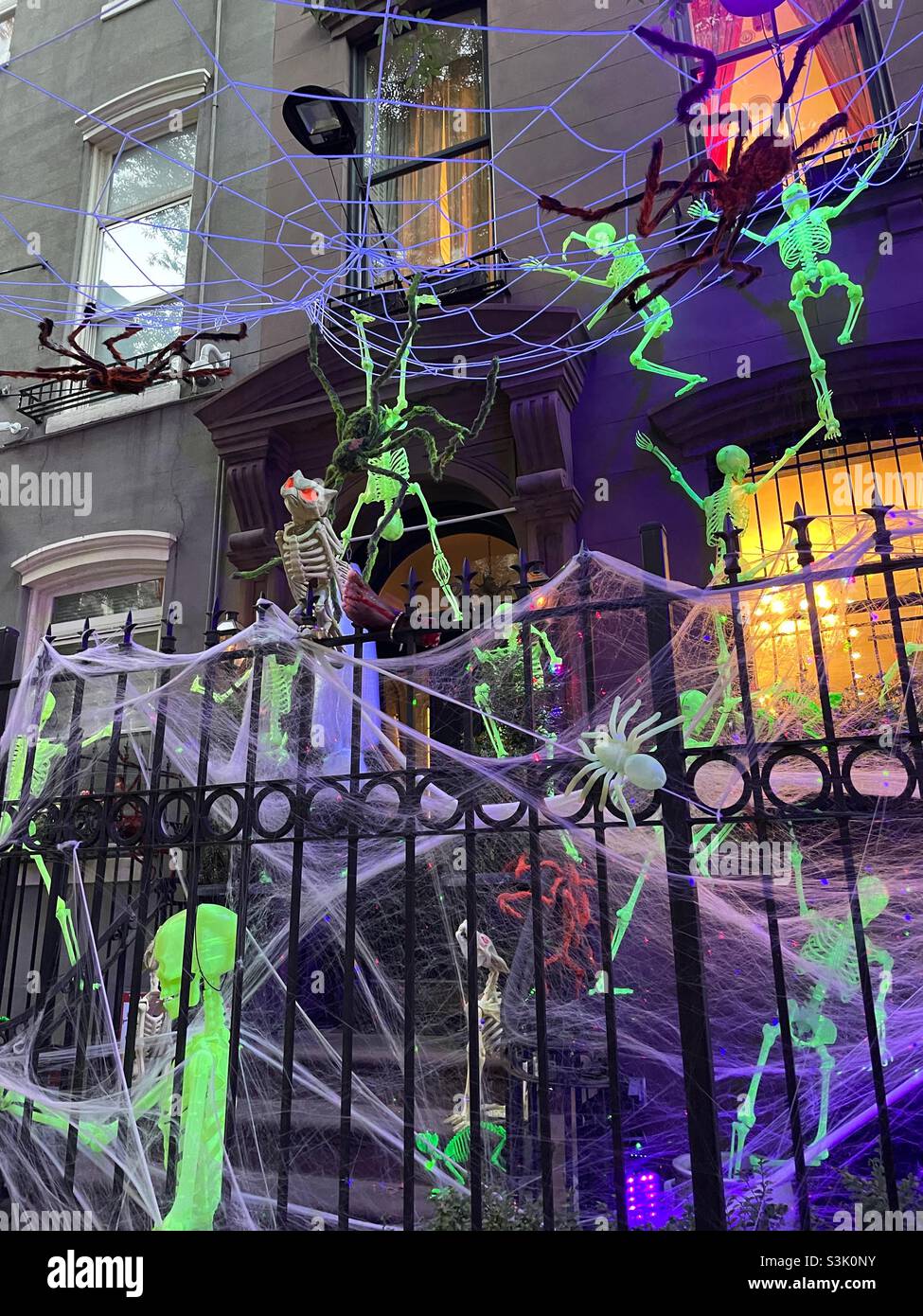 Leuchtende, gut beleuchtete Skelette, die die façade eines Brownstones als Halloween-Dekoration besteigen, Murray Hill, New York City, USA, 2021 - Smartphone-aufgenommenes Stockfoto