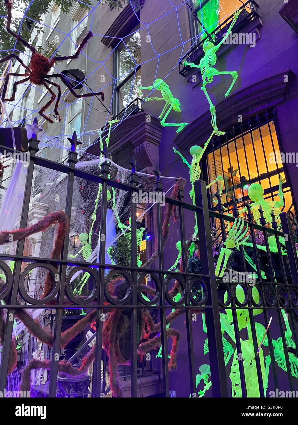 Leuchtende Skelett Halloween Dekorationen hinter schmiedeeisernem Zaun vor einem Brownstone in Murray Hill, 2021, NYC, USA - Smartphone-aufgenommenes Stockfoto