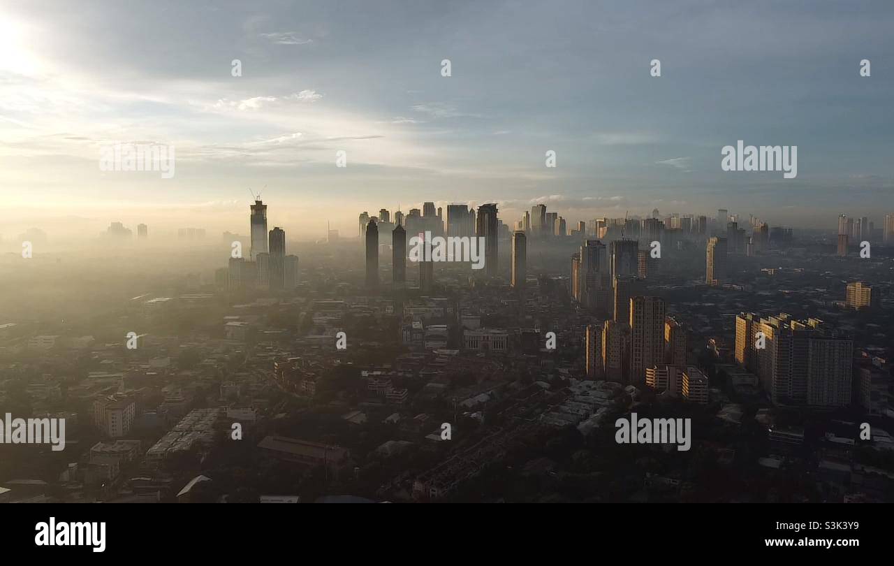 Am frühen Morgen in Quezon City, Philippinen, wo Gebäude teilweise mit Nebel bedeckt sind. - Smartphone-aufgenommenes Stockfoto
