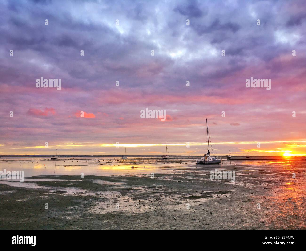 Sonnenuntergang bei Ebbe in Leigh-on-Sea mit kleinen Booten, die auf dem Schlamm der Themse sitzen - Smartphone-aufgenommenes Stockfoto