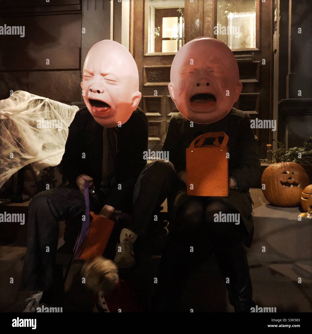 Menschen in Masken geben Süßigkeiten an Trick-or-treaters für Halloween Stockfoto